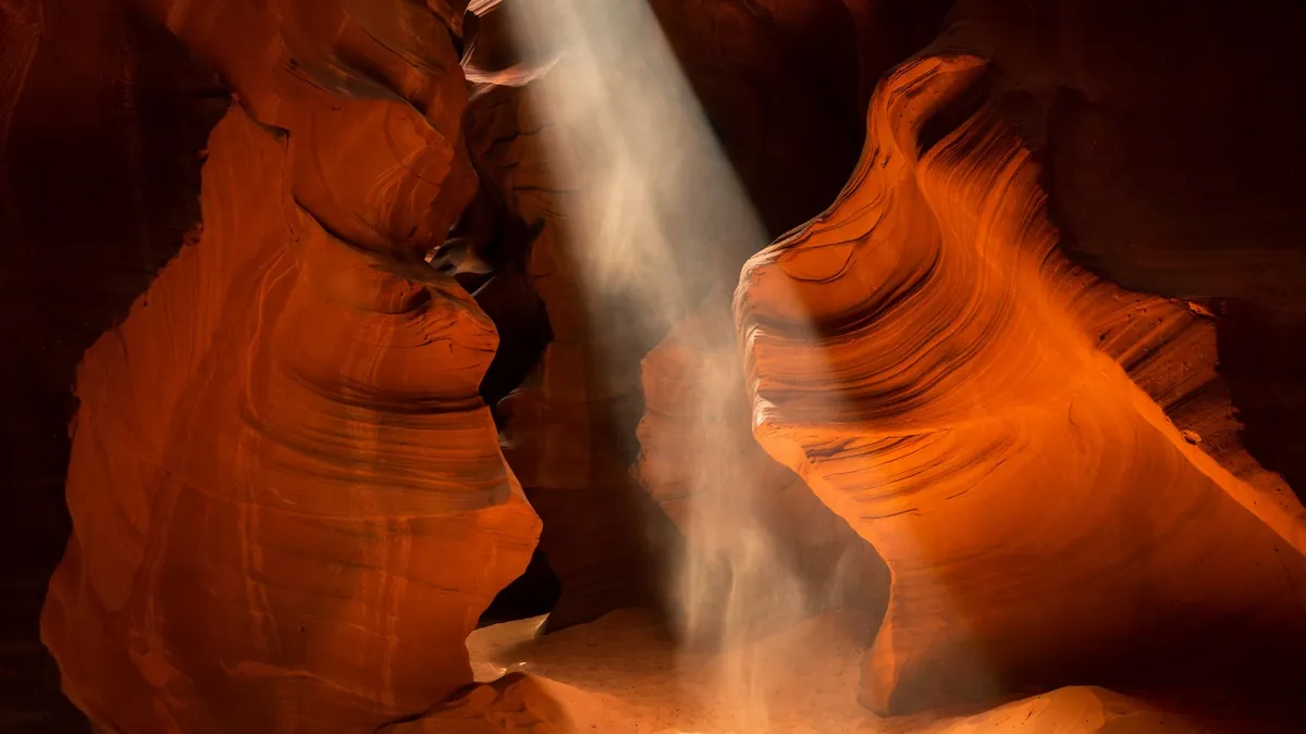 Light beam falling through smooth orange sandstone walls in Antelope Canyon, a surreal place to visit in the US