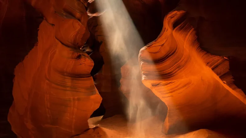 Light beam falling through smooth orange sandstone walls in Antelope Canyon, a surreal place to visit in the US